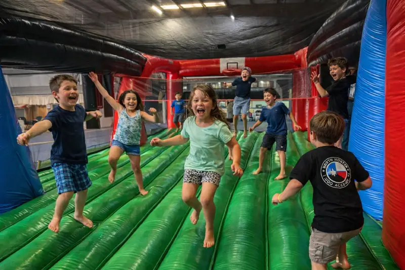 Children running inside inflatable obstacle course at kids birthday party Waco TX